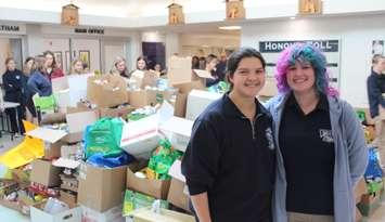 UCC students Amelia Matthews (left) and Sam Stoffyn (right) stand in front of a pile of donations from the Lancers Scare Hunger food drive. November 5, 2024. (Photo by Matt Weverink)