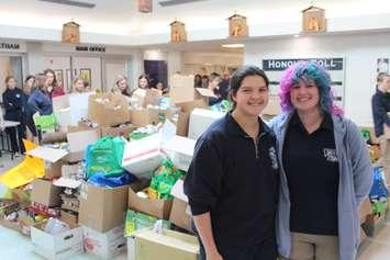 UCC students Amelia Matthews (left) and Sam Stoffyn (right) stand in front of a pile of donations from the Lancers Scare Hunger food drive. November 5, 2024. (Photo by Matt Weverink)