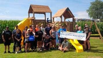Volunteers pose in front of Michael's playset. (Photo courtesy of Chatham-Kent police)