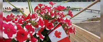 A Canadian flag is seen among red and white flowers (Photo courtesy of Arlette Payne/Facebook)