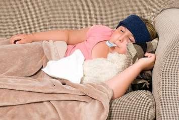 A sick child lays on a couch. File photo courtesy of © Can Stock Photo / dragon_fang