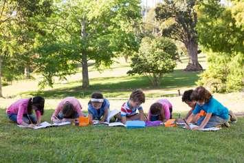 School children doing homework outdoors. © Can Stock Photo / 4774344sean
