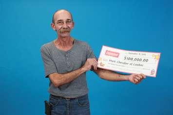 Mark Chevalier holds up a cheque after winning $100,000 with an Instant Extreme Millions scratch ticket. (Photo courtesy of the OLG)