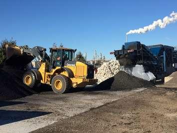 A front end loader mixes a new type of pot hole filling asphalt being made and sold at Pebbles Gravel and Topsoil. (Photo by Mike James)