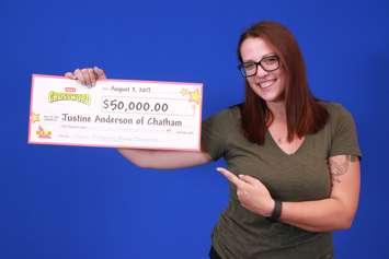 Justine Anderson holds up her Instant Crossword winnings. (Photo courtesy of OLG)