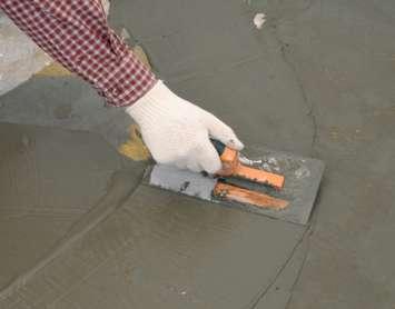 Construction worker with trowel spreading wet concrete. (© Can Stock Photo / Stockphoto)